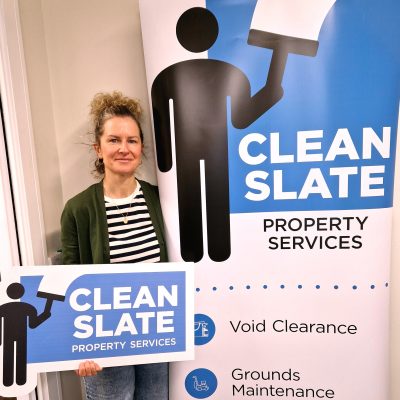 Woman standing in front of a pull-up banner that says Clean Slate Property Services