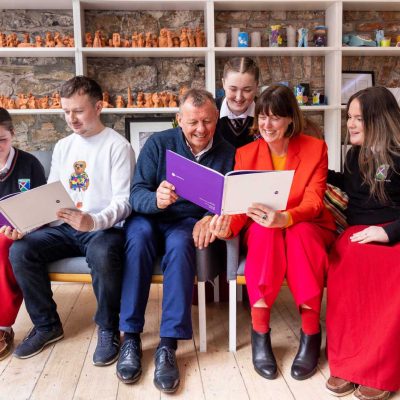 A group of six people looking at reports of Narrative4's work and smiling.