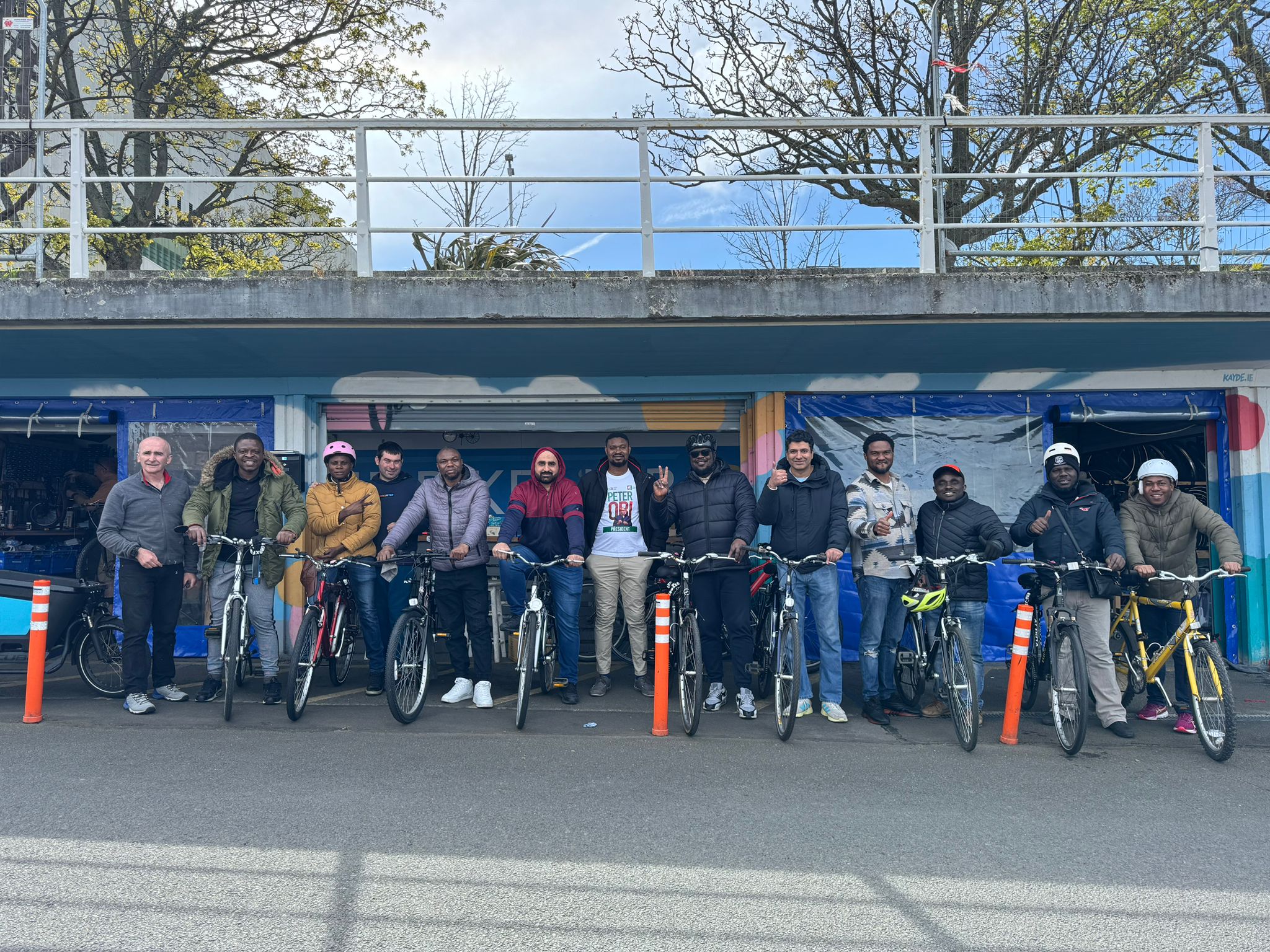 Line of people standing beside bikes under a canopy