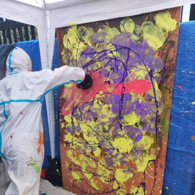 Person in full Protective gear punching an easel with paint