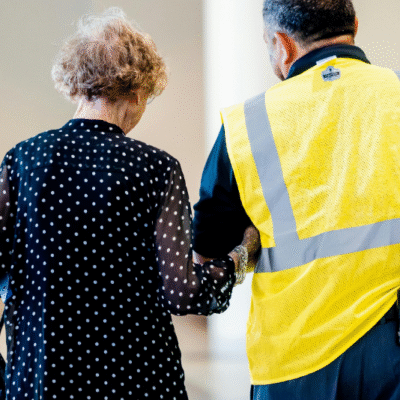 Man acting as security personnel guiding elderly woman by linking