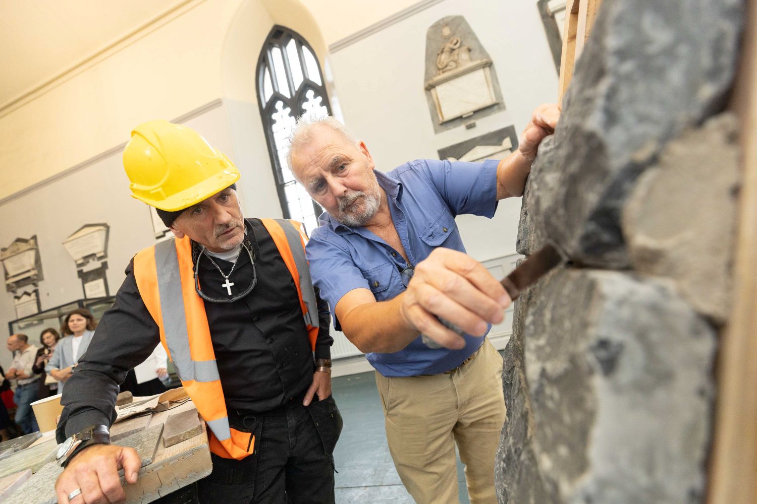 Person showcasing stone masoning to a workshop participant