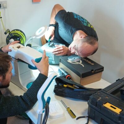 2 men working on repairs on a sewing machine