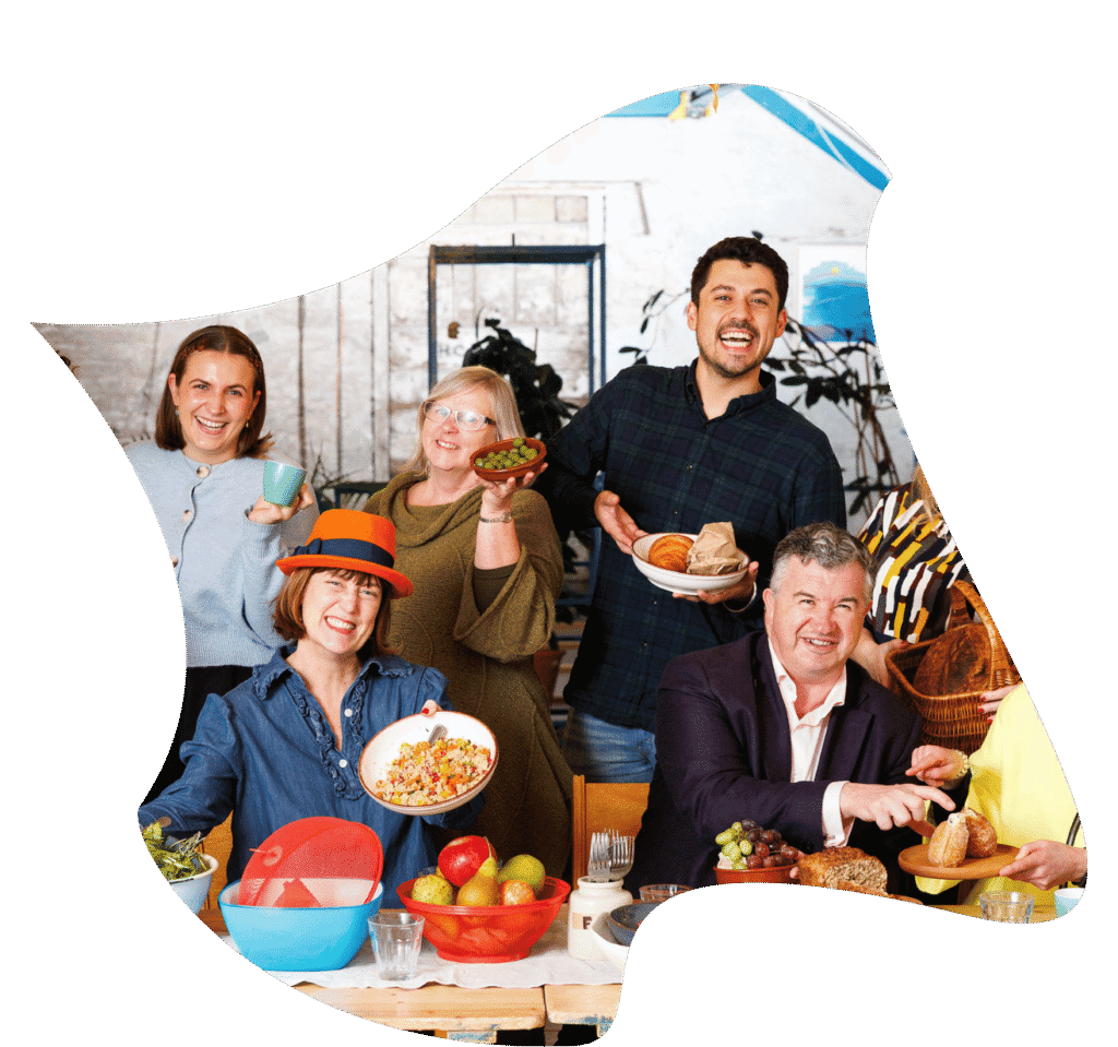 People smiling by a table , holding up food
